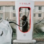 a dog sitting in a charging station next to a white car